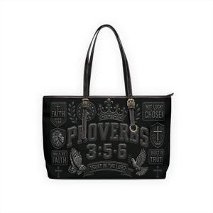 A black tote bag with a distressed gray graphic print featuring the text 'PROVERBS 3:5-6' and various religious-themed badges, shown against a plain white background.