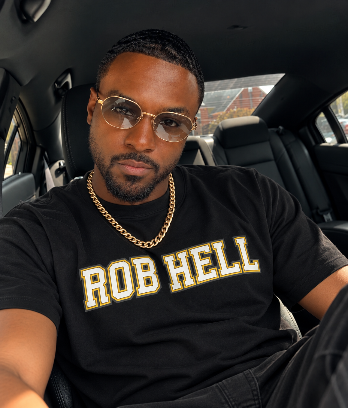 Stylish man in a car wearing a black tee with the text "ROB HELL" on it.